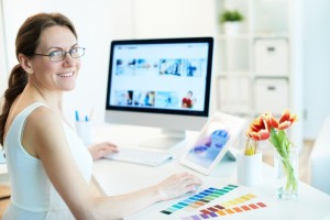 Portrait of happy female designer working and looking at camera